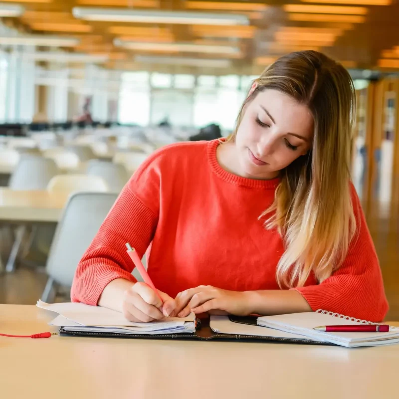 Portrait of young student studying at the university library. Education and lifestyle concept.